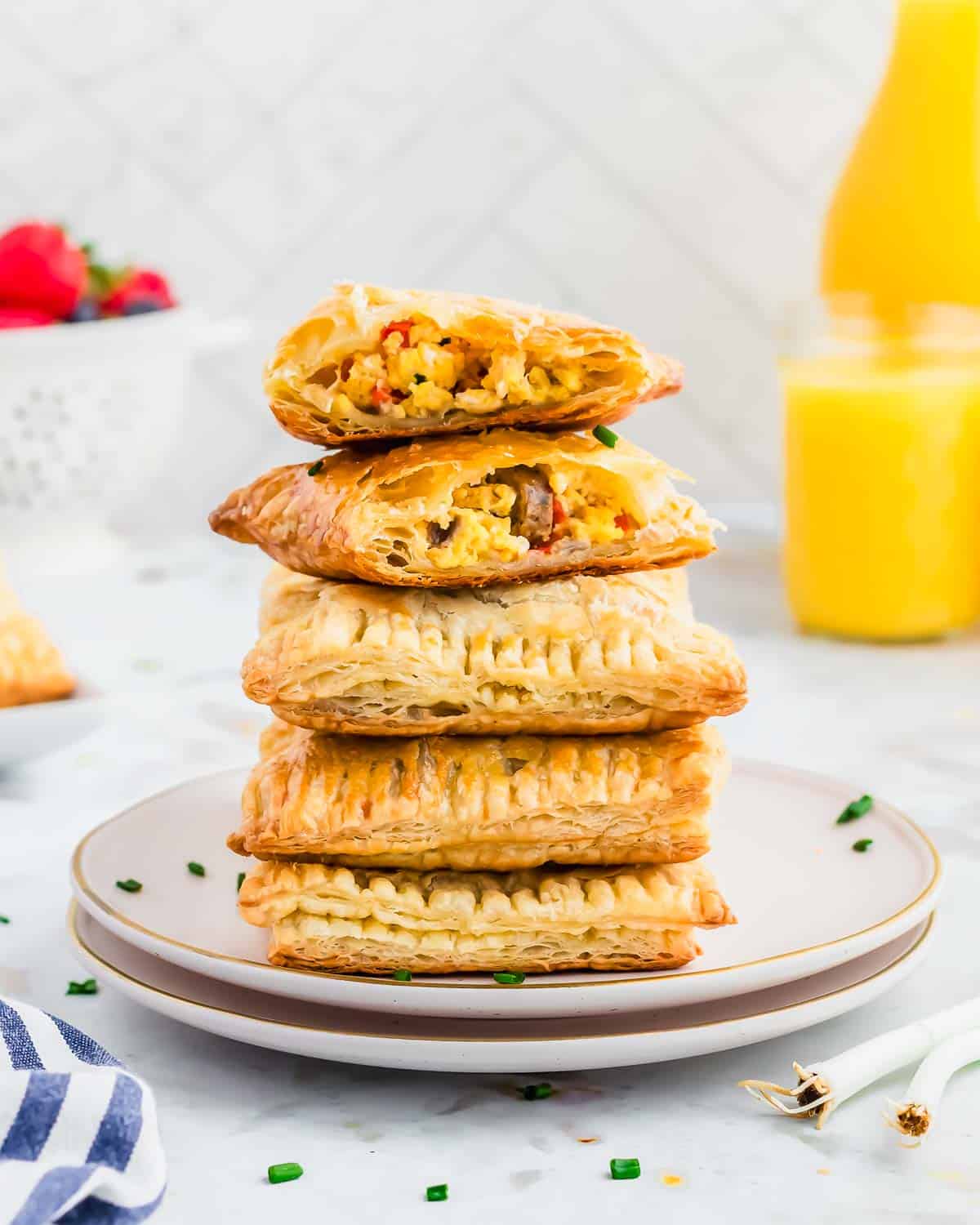 Homemade breakfast hot pockets stacked on two white plates with egg, cheese and sausage filling.