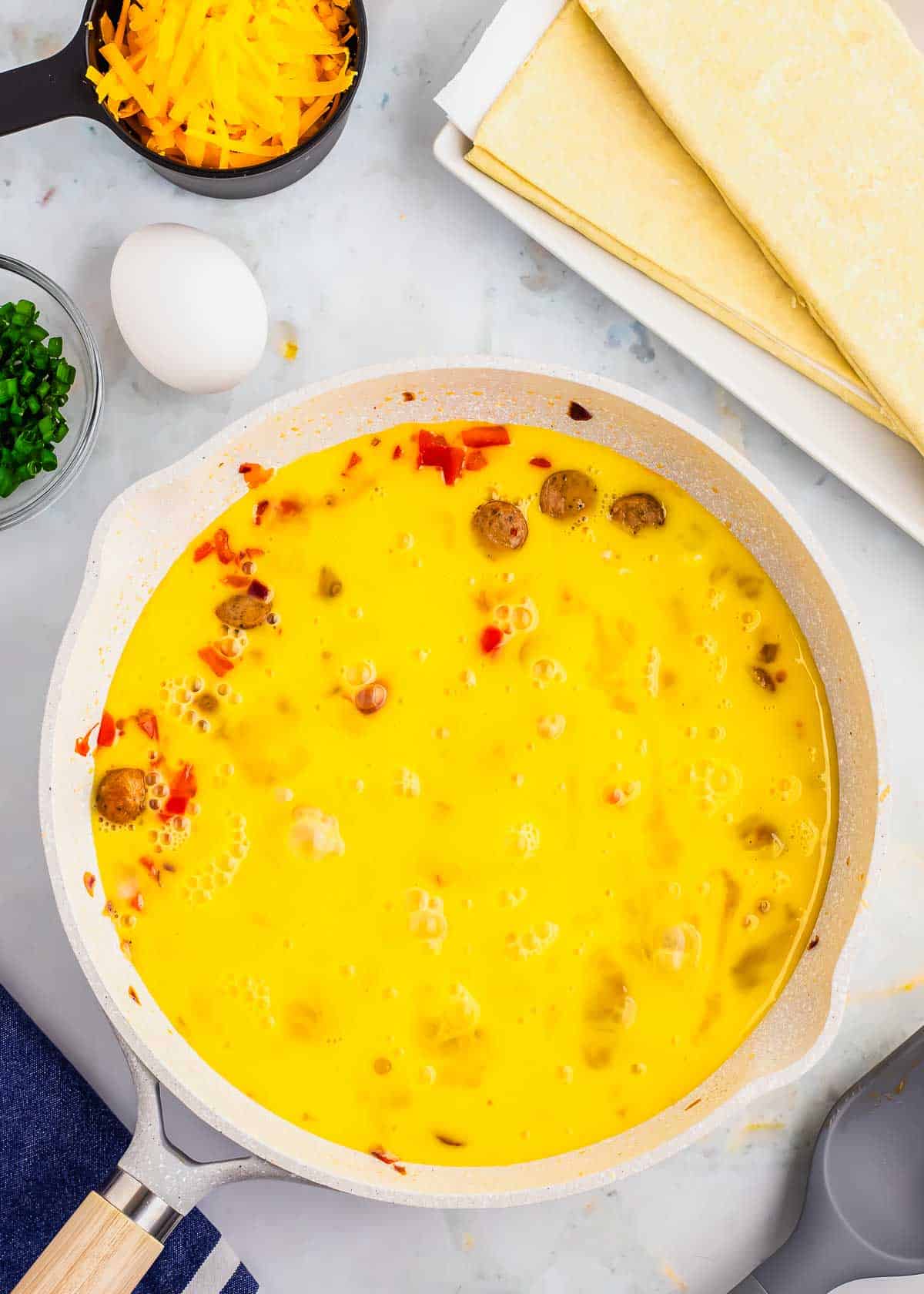 A skillet full of eggs, cheese, and other ingredients.