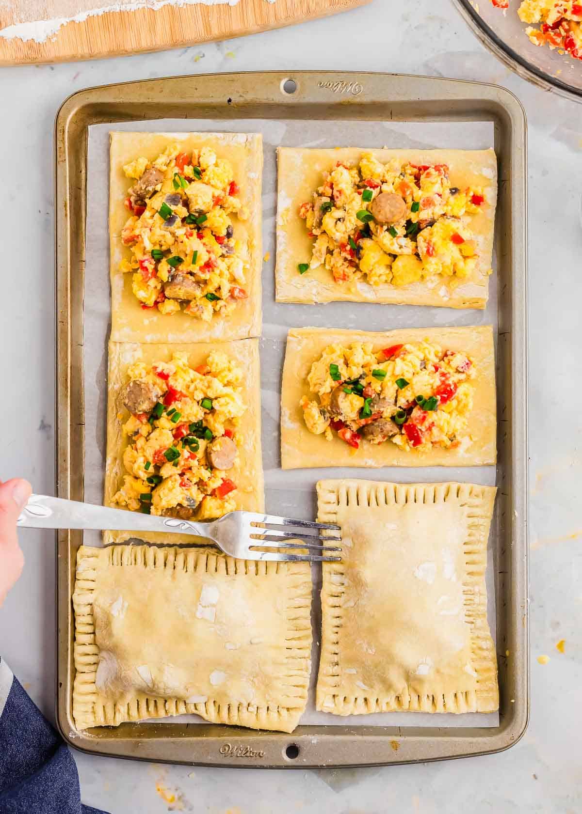 Using a fork to crimp the edges of breakfast hot pockets.