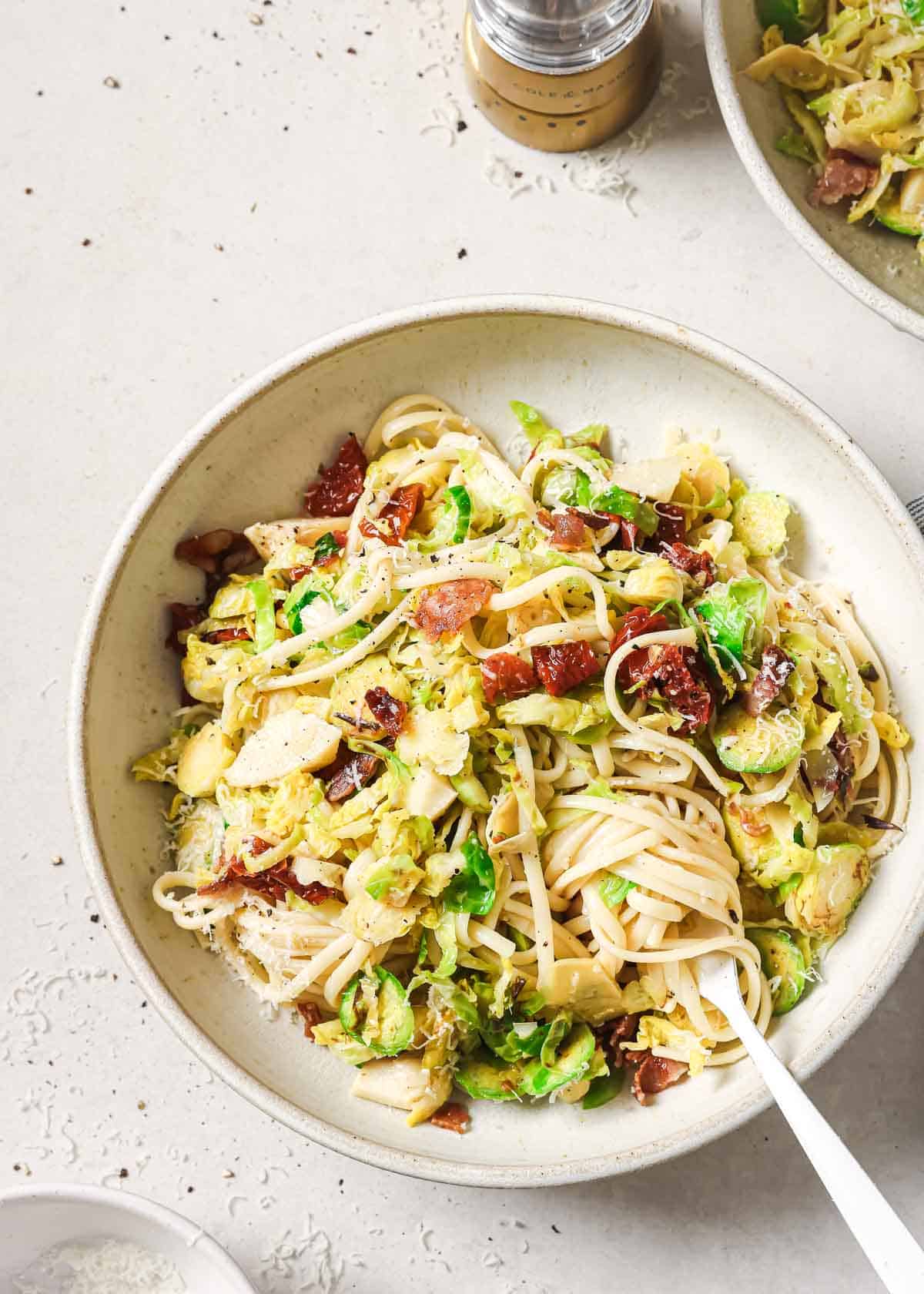 Brussels sprouts and bacon pasta in a bowl twirled around a fork.