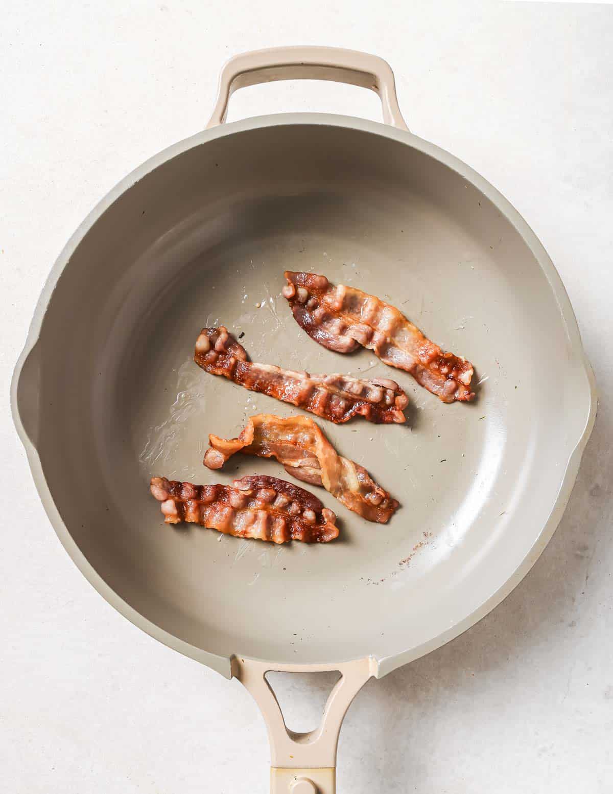 A frying pan with bacon in it.
