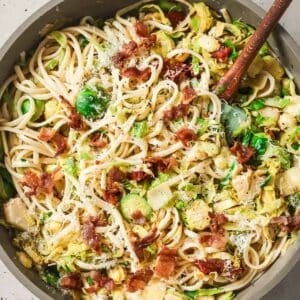 A skillet filled with pasta, bacon and brussels sprouts.