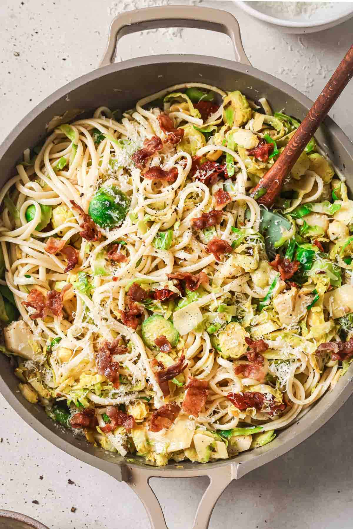 A skillet filled with pasta, bacon and brussels sprouts.