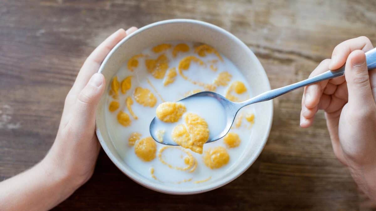 A woman's hand is holding a bowl of cereal.