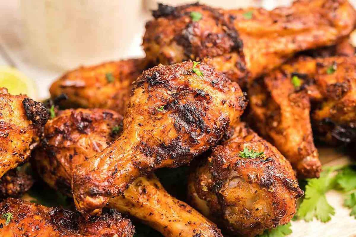 Grilled chicken wings on a plate with a lime wedge.