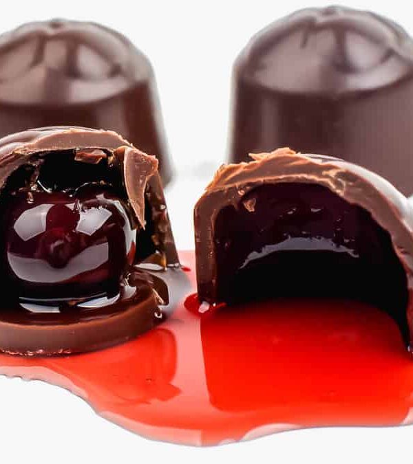 Three chocolates with red liquid on top of them.
