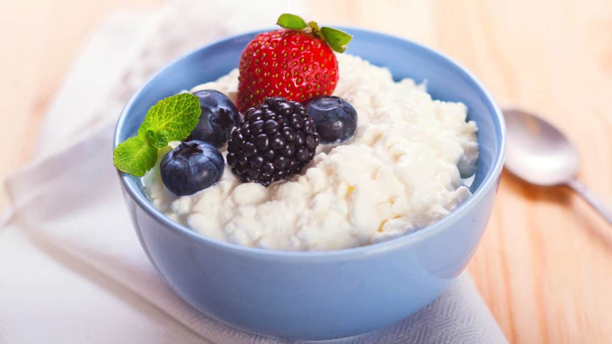 A bowl of yogurt with berries and a spoon.