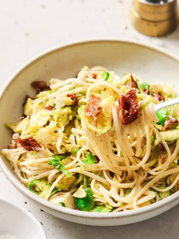 A bowl of pasta with bacon and brussels sprouts.