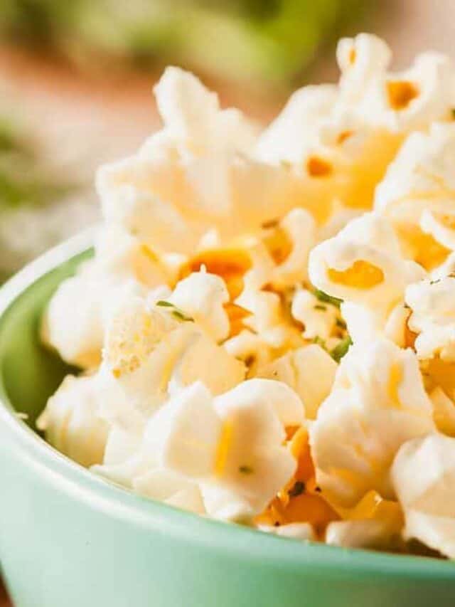 Close-up of a bowl of freshly popped popcorn with visible salt and herbs, suggesting a flavored variety.