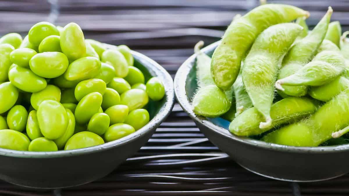 Two bowls of green beans on a mat.