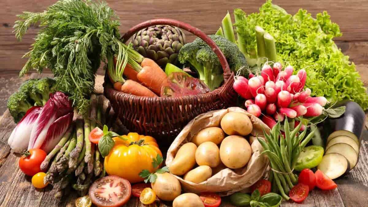 A basket full of vegetables on a wooden table.