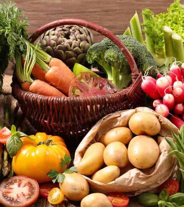 A basket full of vegetables on a wooden table.