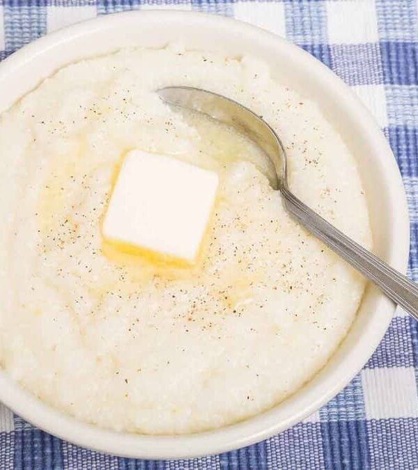 A bowl of mashed potatoes with butter and a spoon.