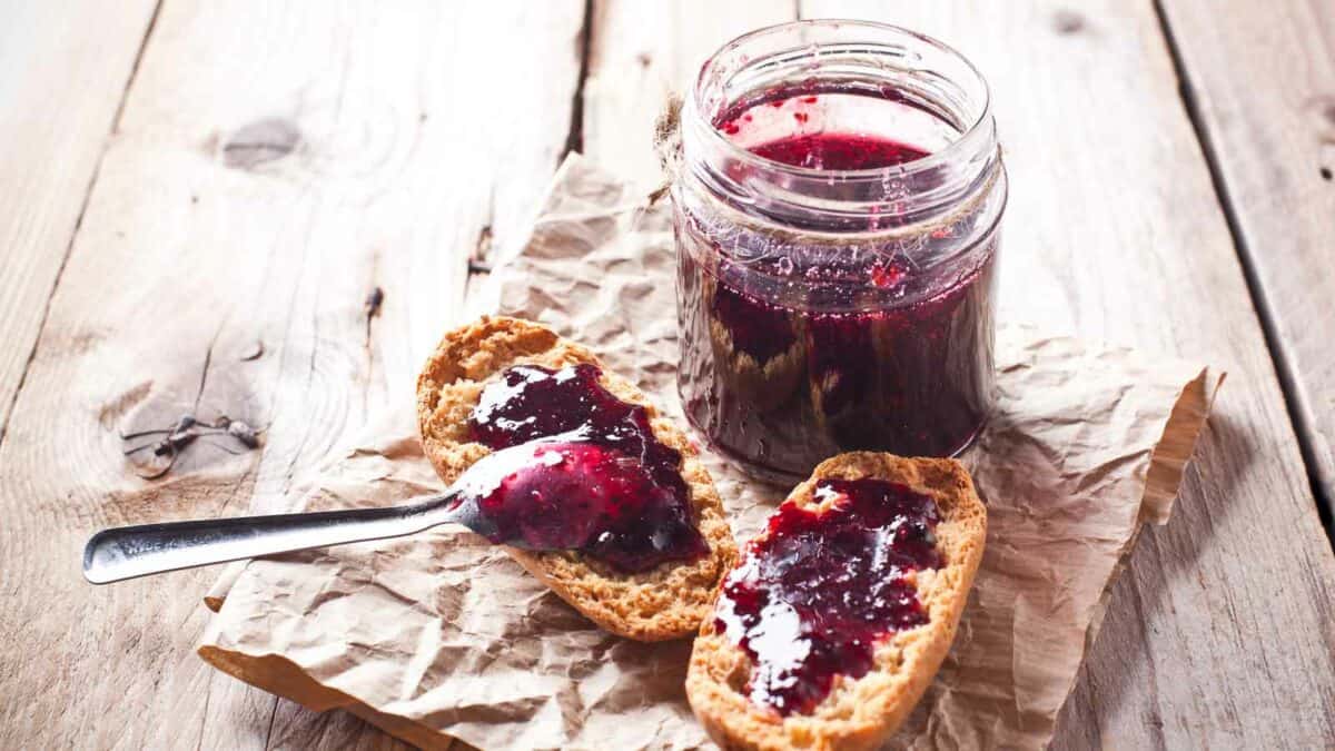 A jar of jam and toast with a spoon.