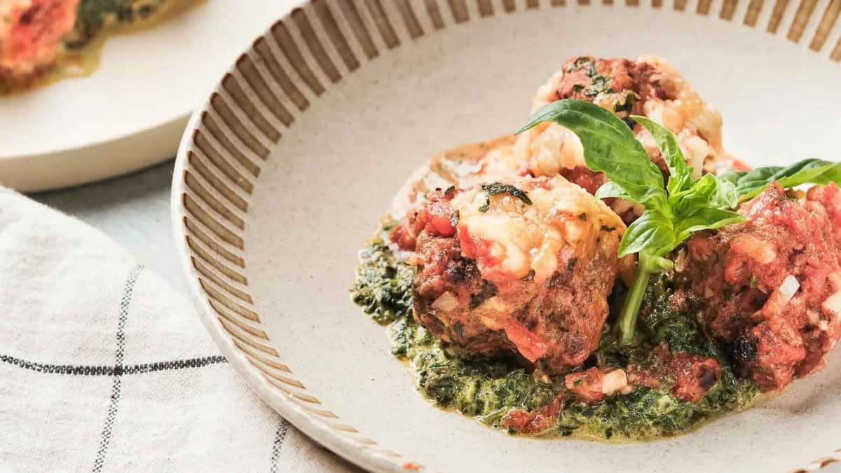 A plate with meatballs and spinach on it.