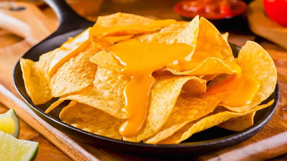 Nachos with cheese in a skillet on a cutting board.