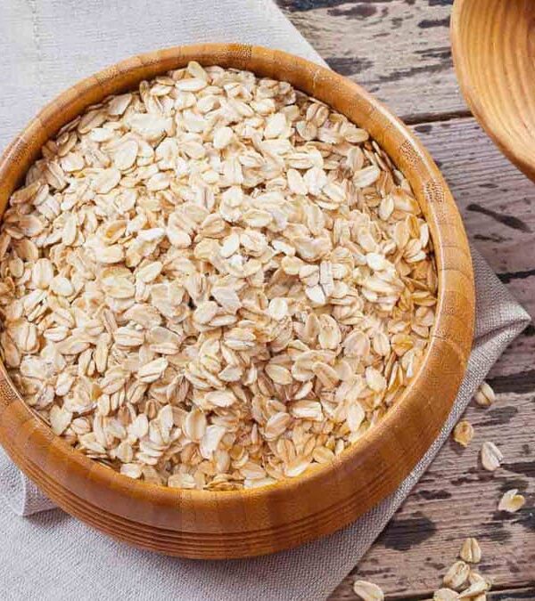 Oats in a wooden bowl on a wooden table.