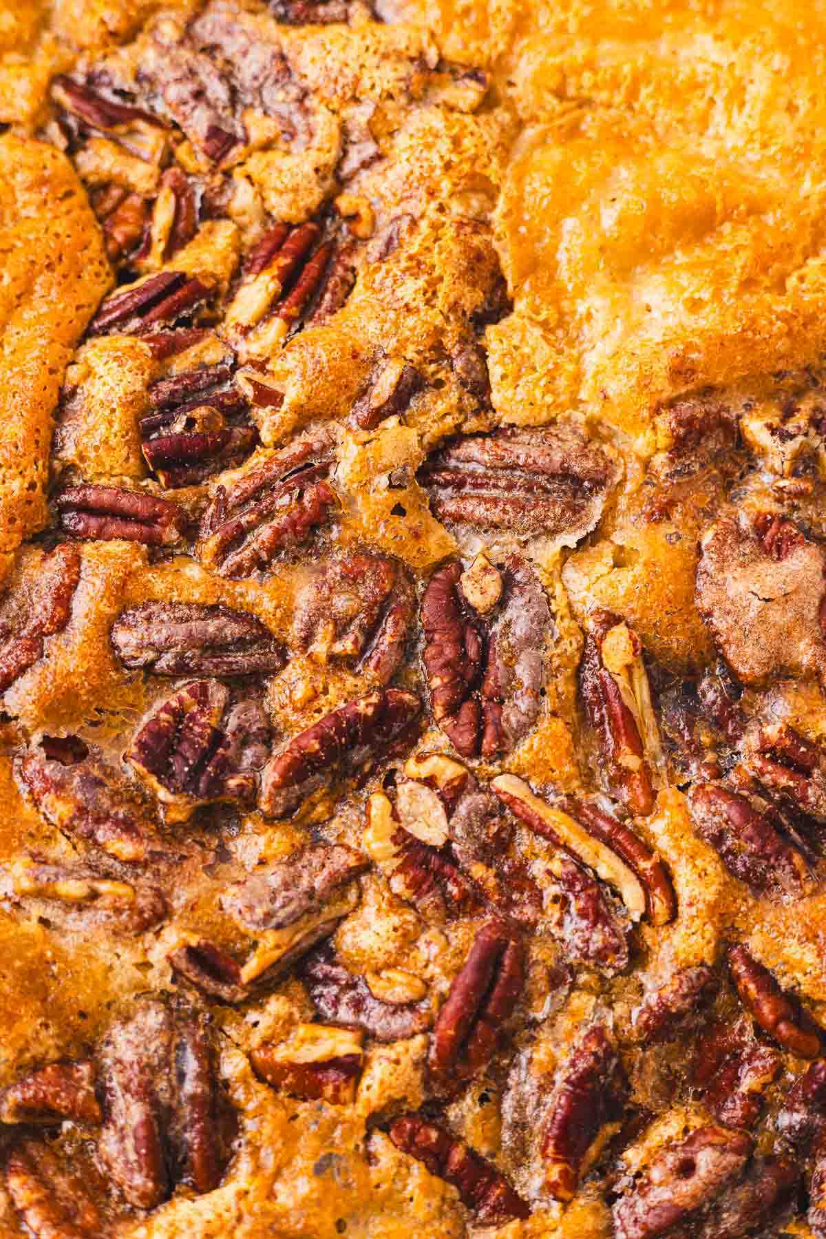 A close up of a cobbler with pecans on it.