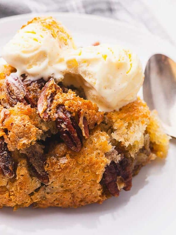 Pecan cobbler with ice cream and pecans on a plate.