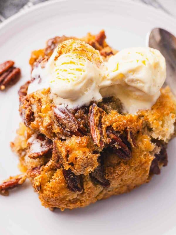 Pecan bread cobbler with ice cream and pecans on a plate.