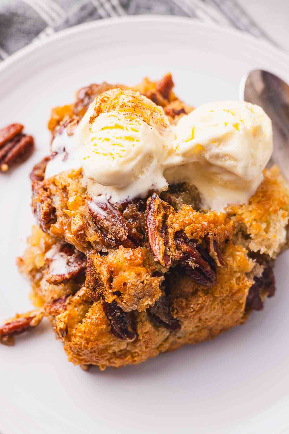 Pecan bread cobbler with ice cream and pecans on a plate.