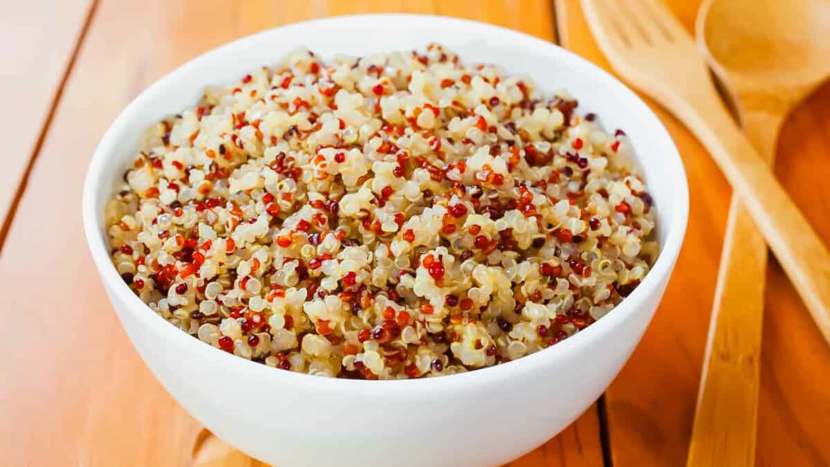 Quinoa in a white bowl on a wooden table.