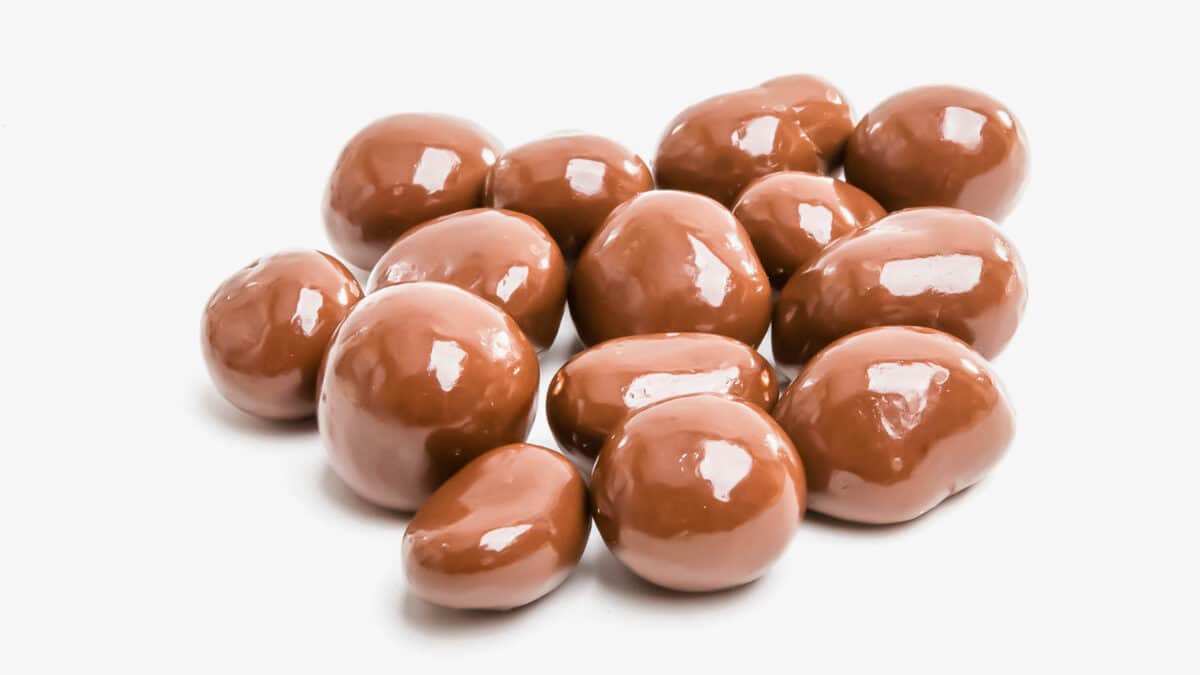 A pile of chocolate covered almonds on a white background.