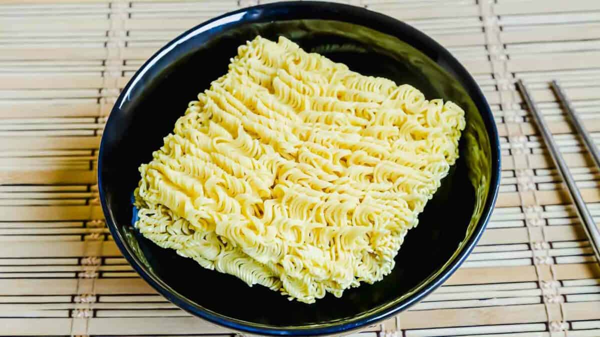 A bowl of noodles with chopsticks on a bamboo mat.