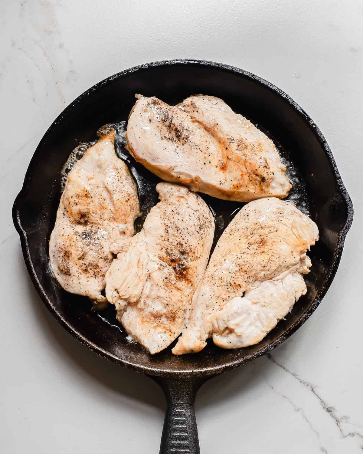Chicken breasts in a cast iron skillet.