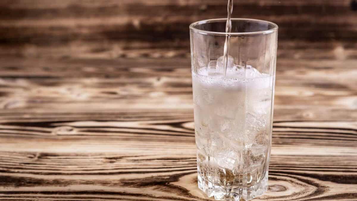A glass of water with ice being poured into it.