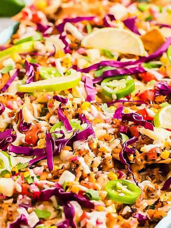 A dish of nachos with slaw and limes.