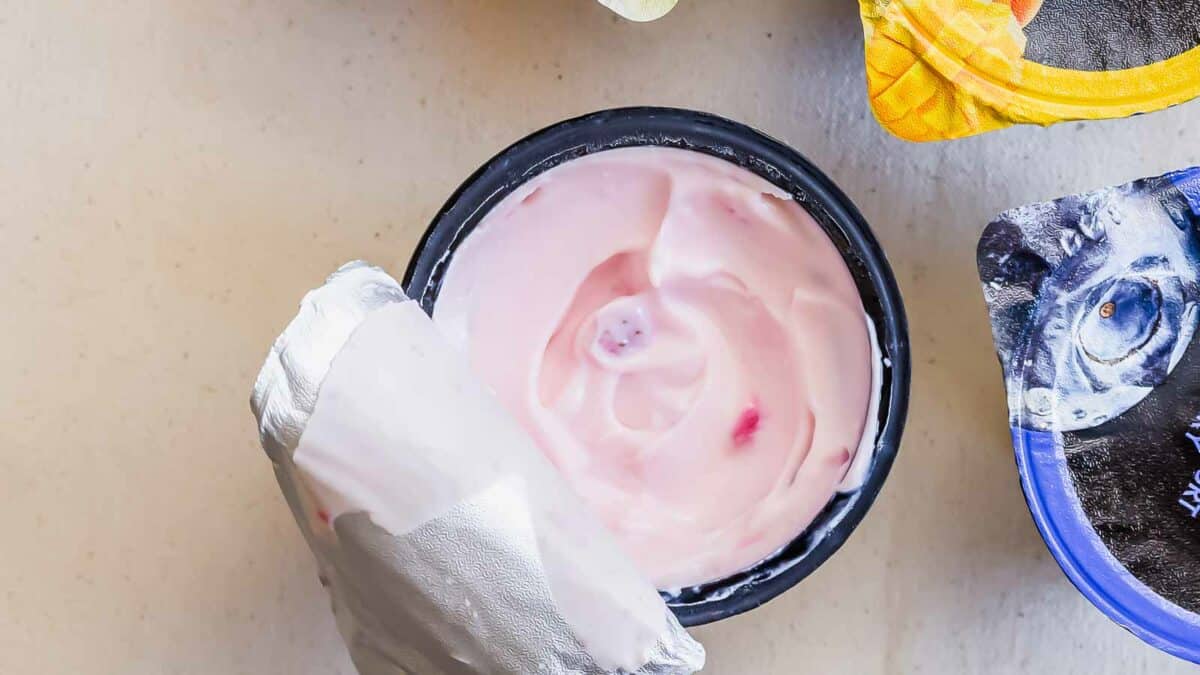 A bowl of yogurt and a plastic container on a table.