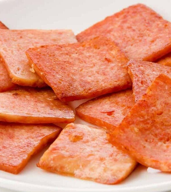 A white plate with pieces of meat on it.