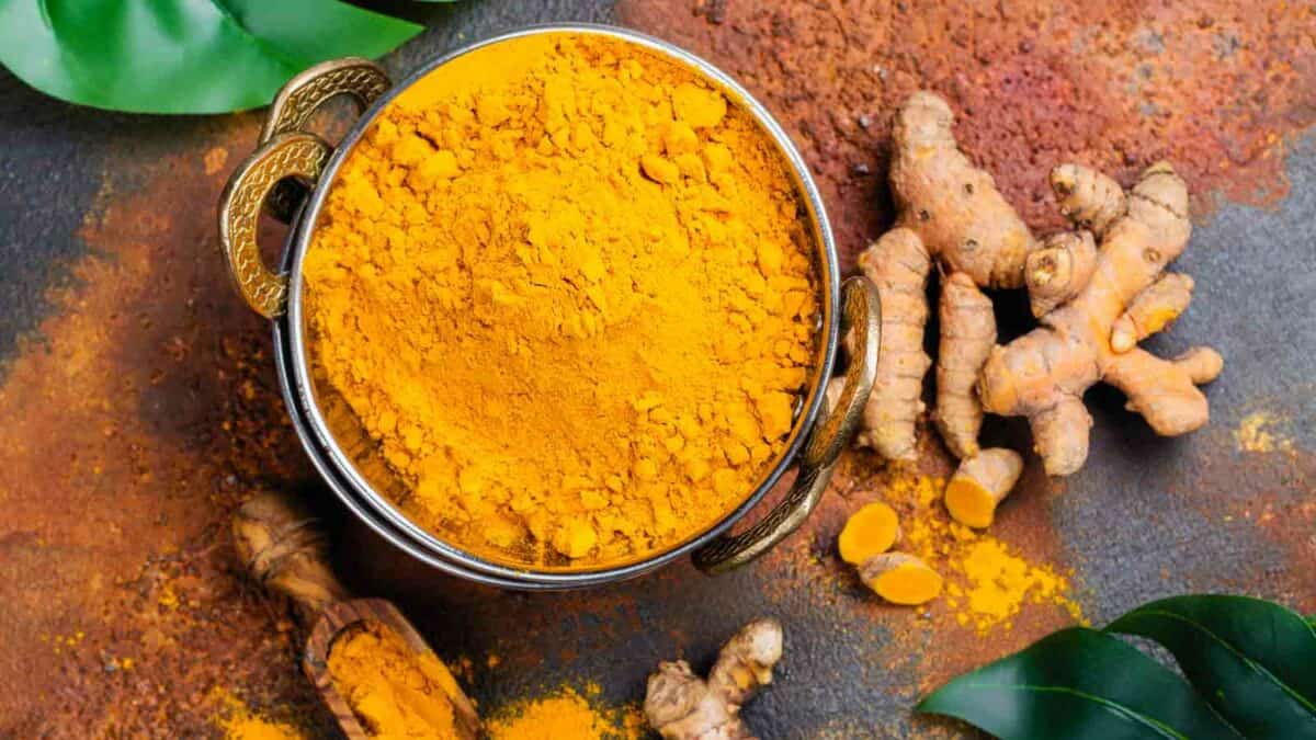 Tumeric powder and leaves on a dark background.