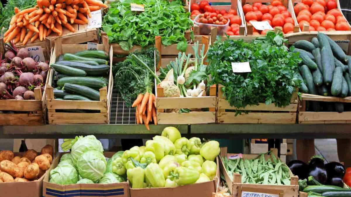 A variety of vegetables are displayed in crates at a market.