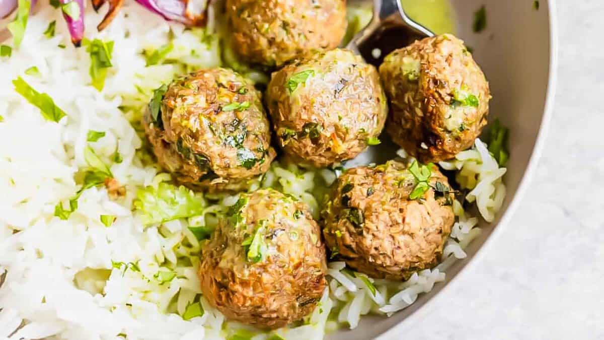 A bowl of rice with meatballs on top.