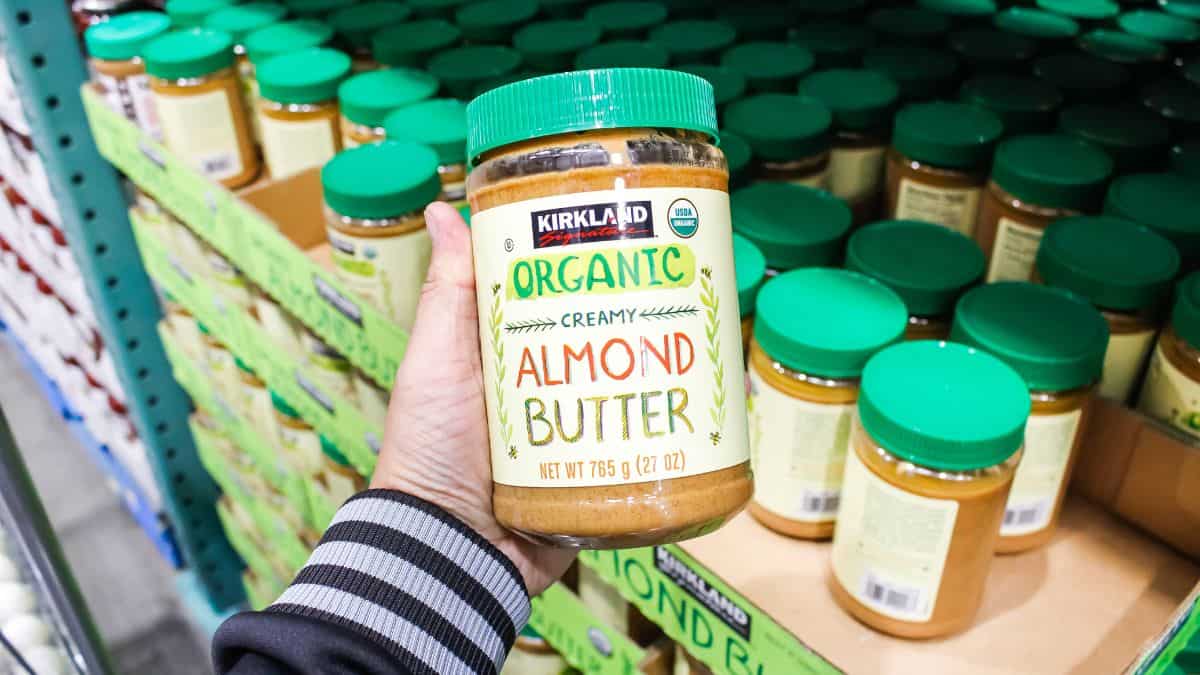 A person holding a jar of almond butter.