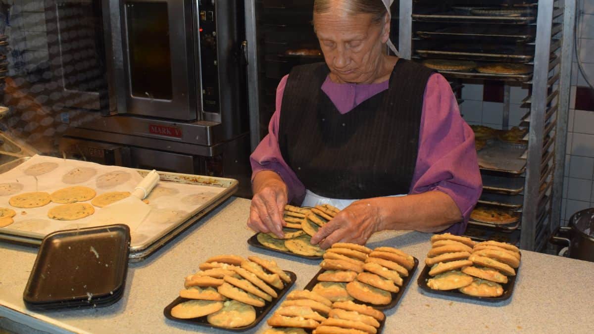 A woman is preparing cookies in a kitchen.