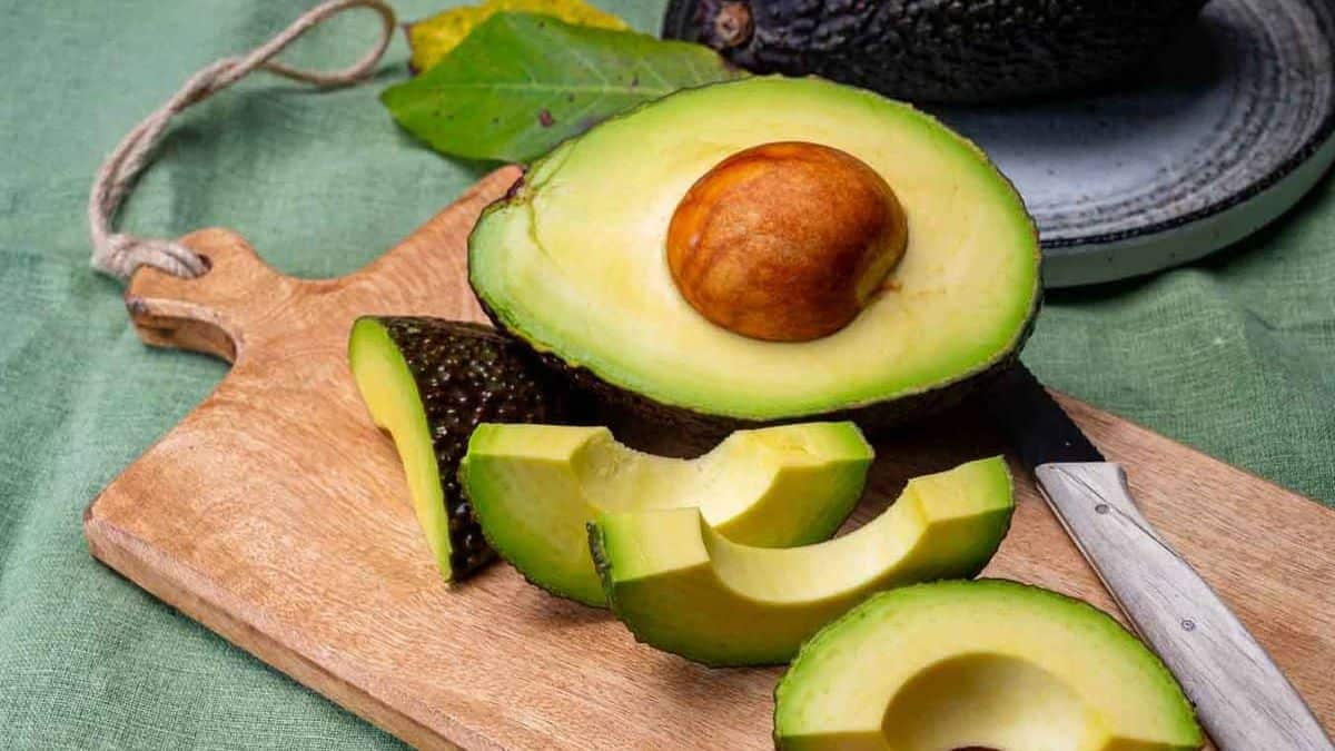 Avocado on a cutting board with a knife.