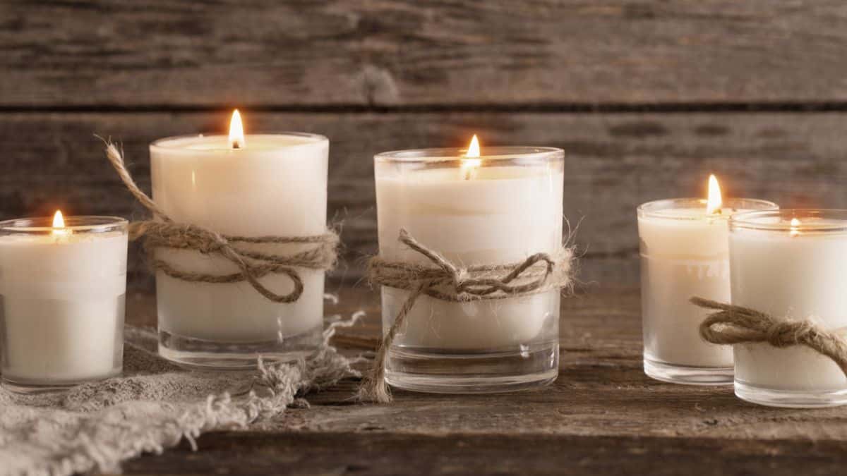 A group of white candles on a wooden table.