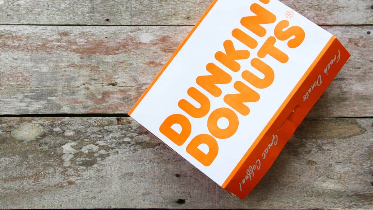 An orange and white dunkin' donuts box on a wooden surface.