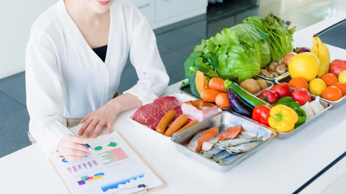 Nutritionist with a selection of healthy foods and a dietary chart on the table.