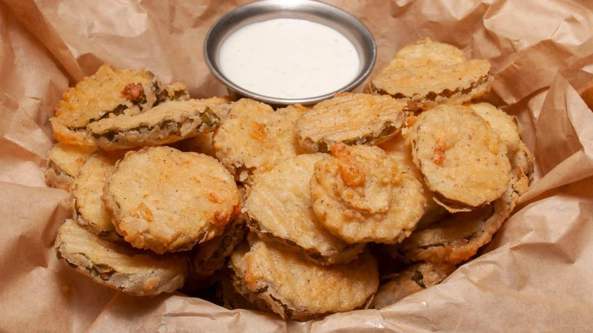 Fried pickles in a brown paper bag with dipping sauce.