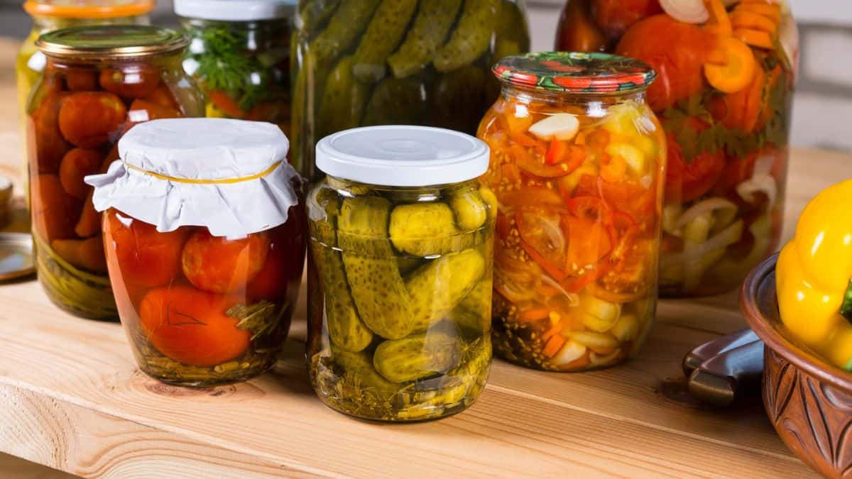 Jars of pickles and tomatoes on a table.