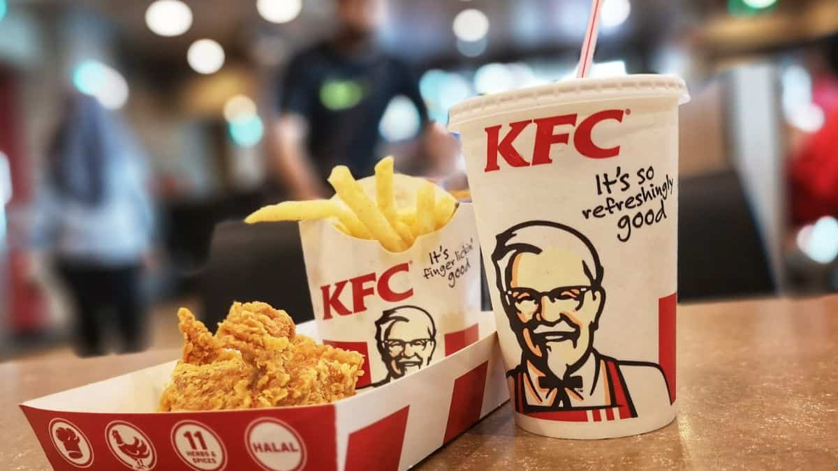 Kfc meal with fried chicken, fries, and a soda on a table.
