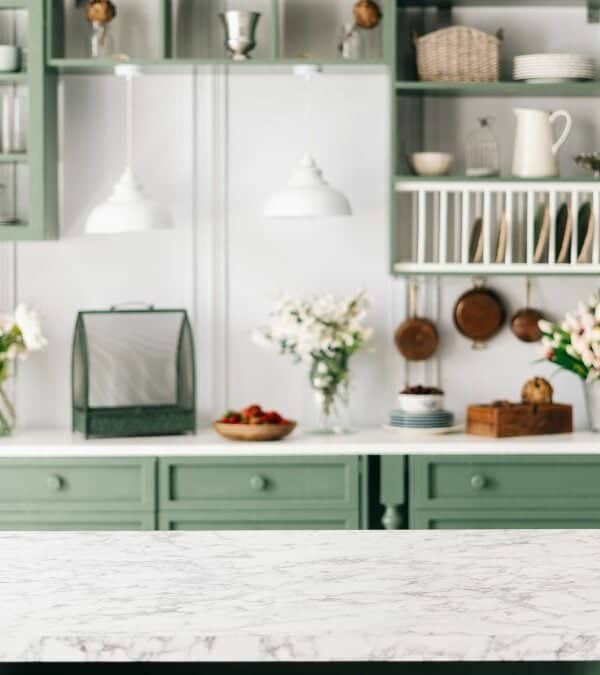 Bright kitchen interior with green cabinetry and marble countertop, free from things not to keep on the kitchen counter.