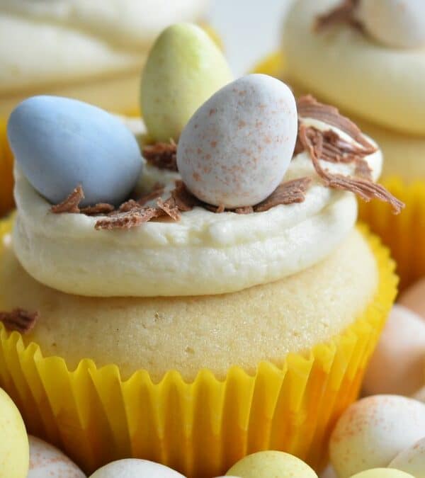Cupcakes decorated with frosting and topped with candy eggs to resemble bird nests.