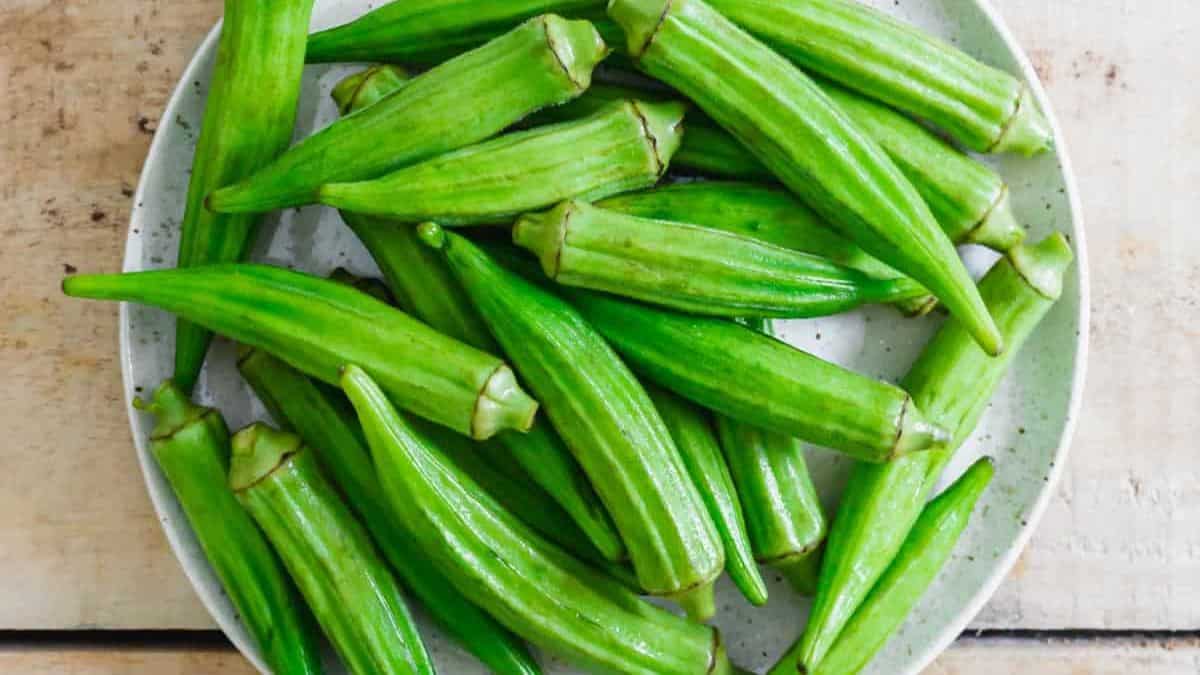 A plate of green okra on a wooden table.