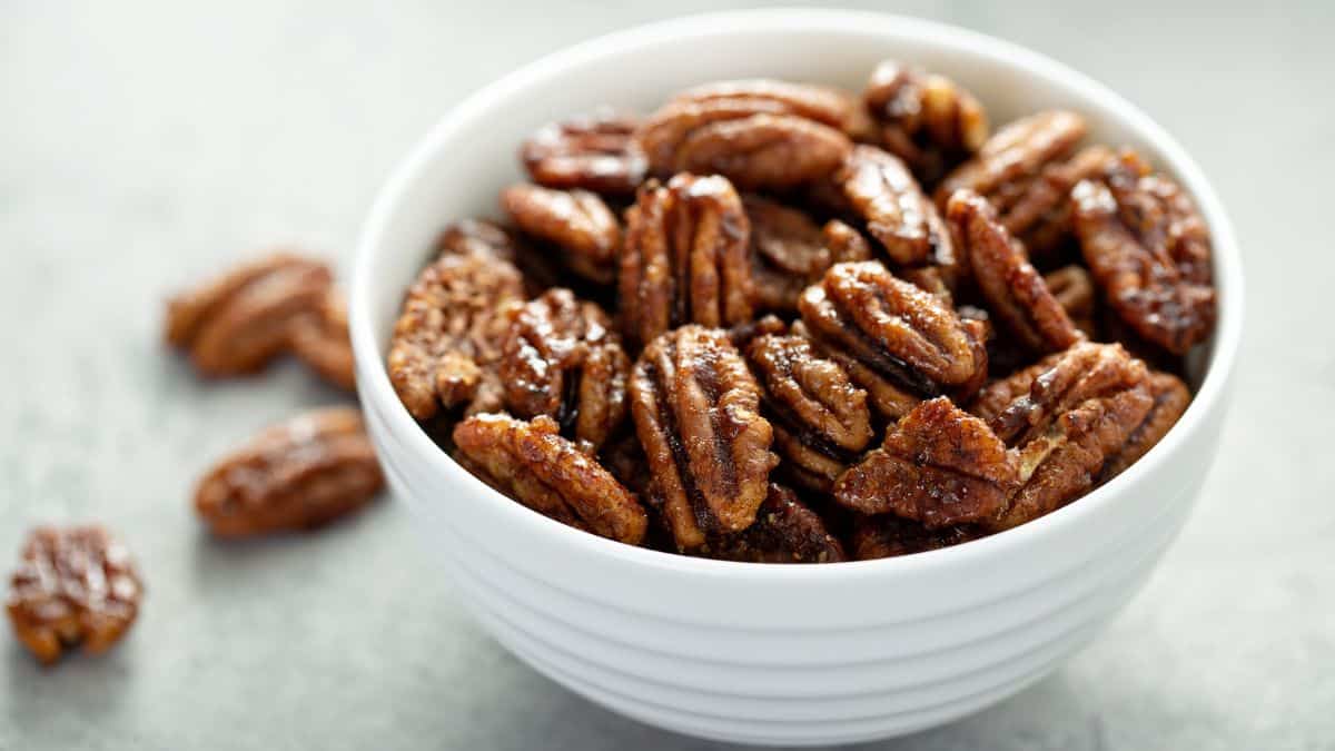 Pecans in a white bowl on a grey surface.