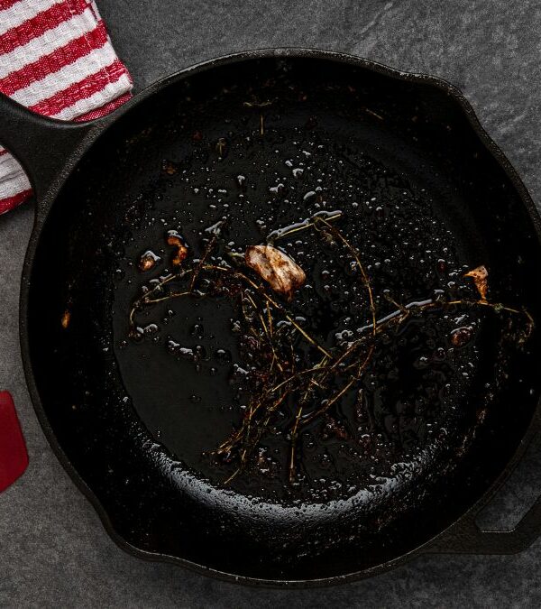 A frying pan with salt and a brush next to it.